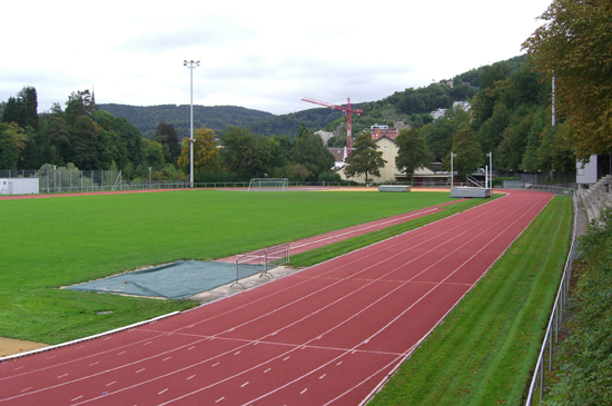 Aussenanlage mit Bahnen und Innenwiese, im Hintergrund Sporthalle der Sportanlage Aue in Baden